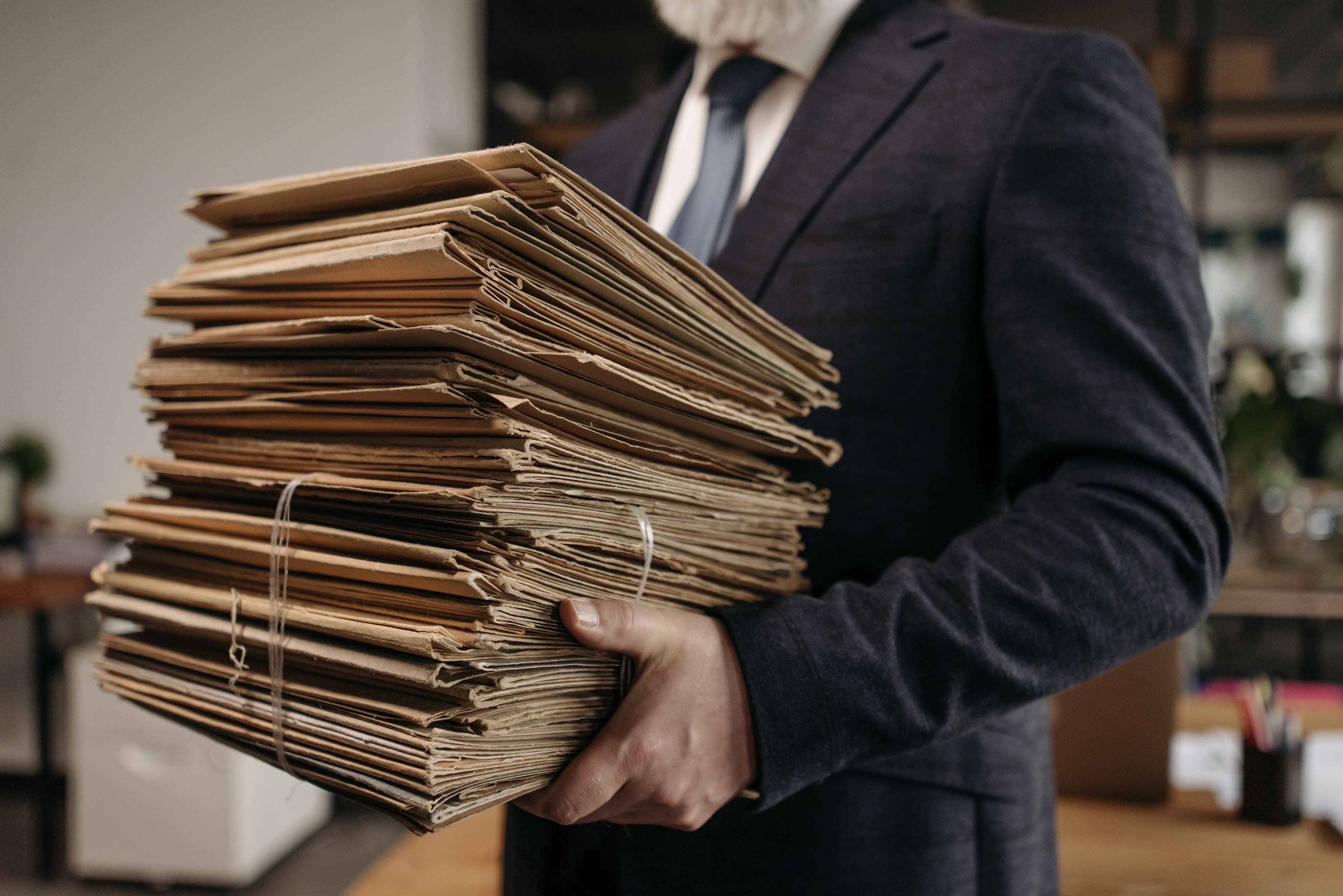 A person carrying a stack of tied paper files